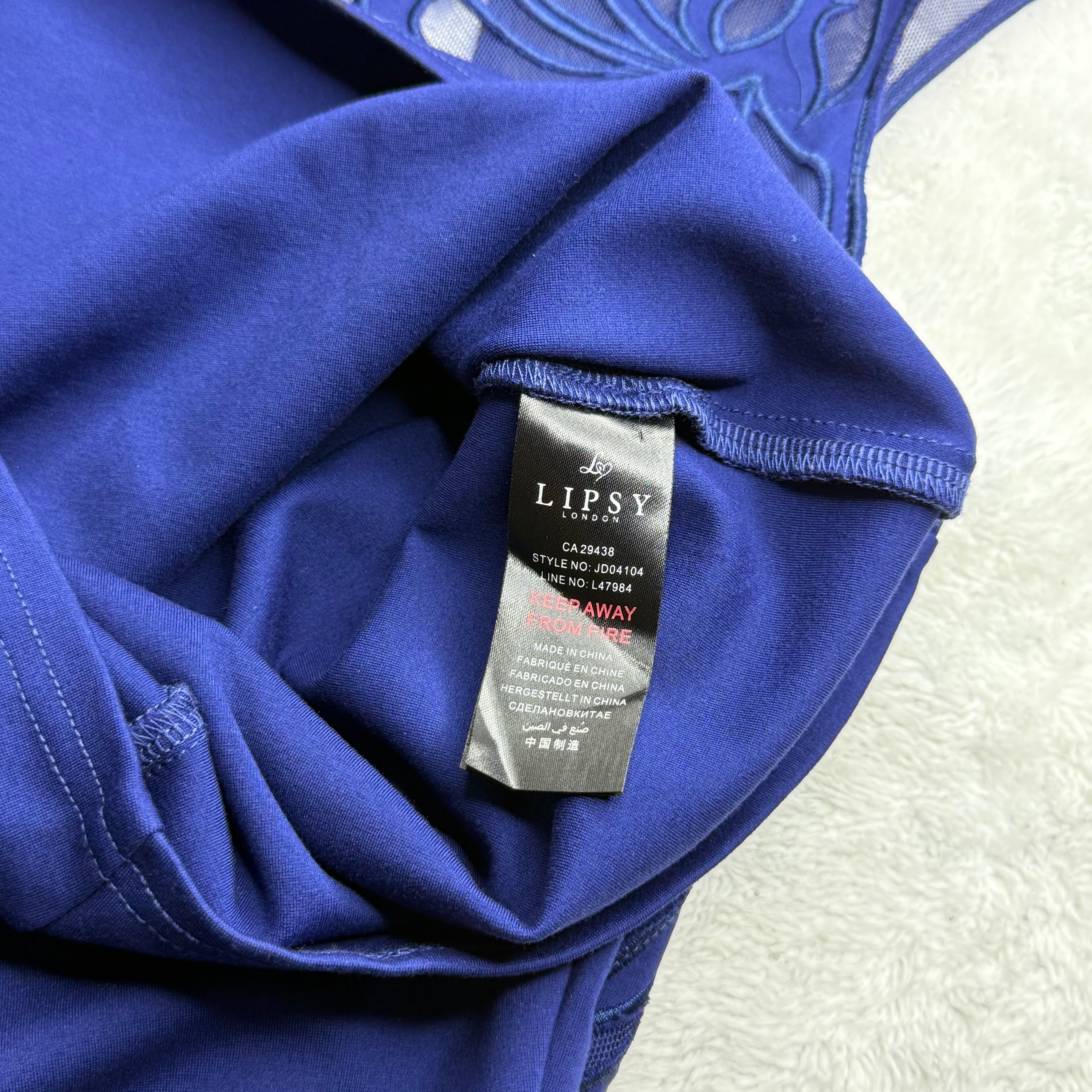 Close-up of a blue garment with a Lipsy tag on a textured white background