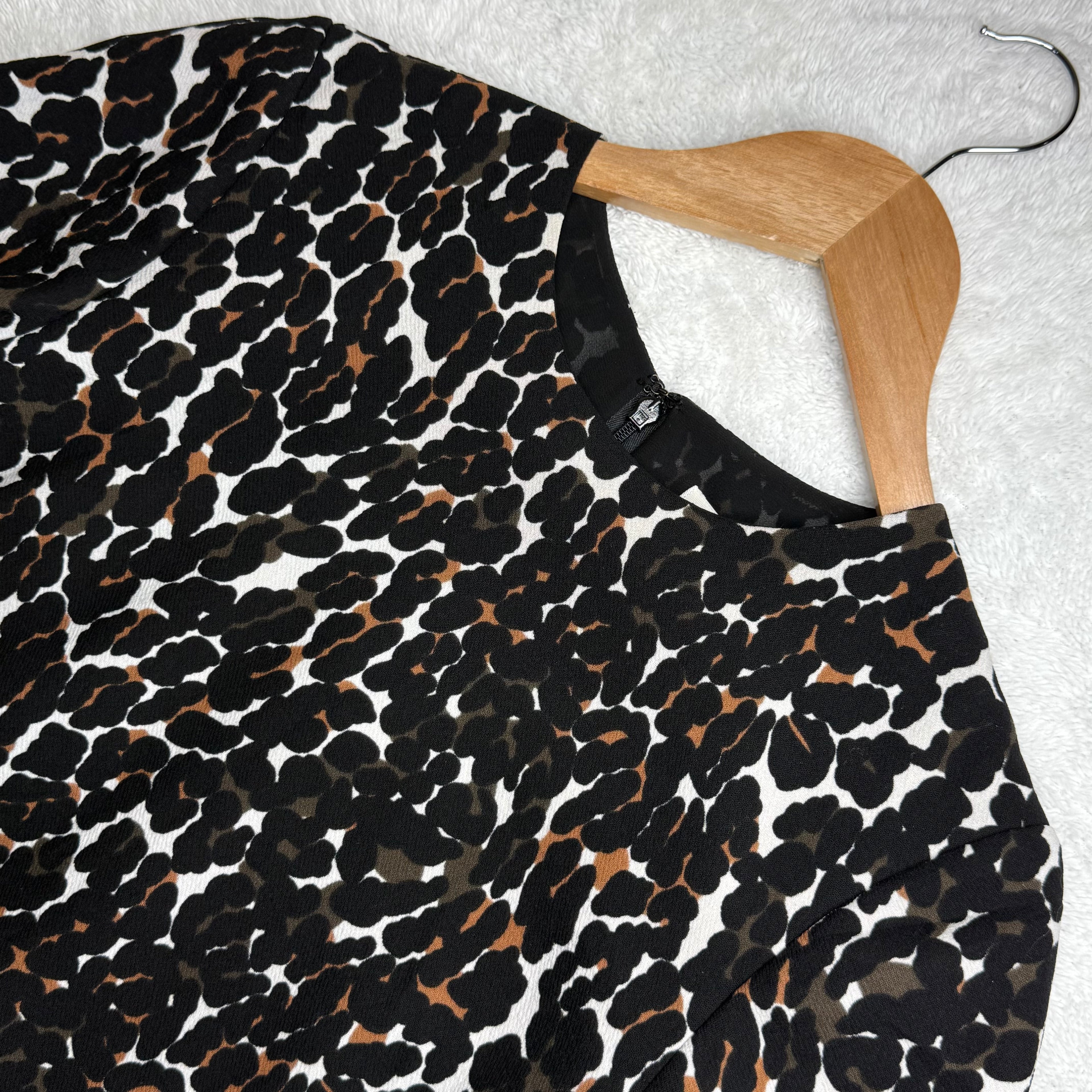 Leopard print dress on a wooden hanger against a light gray background