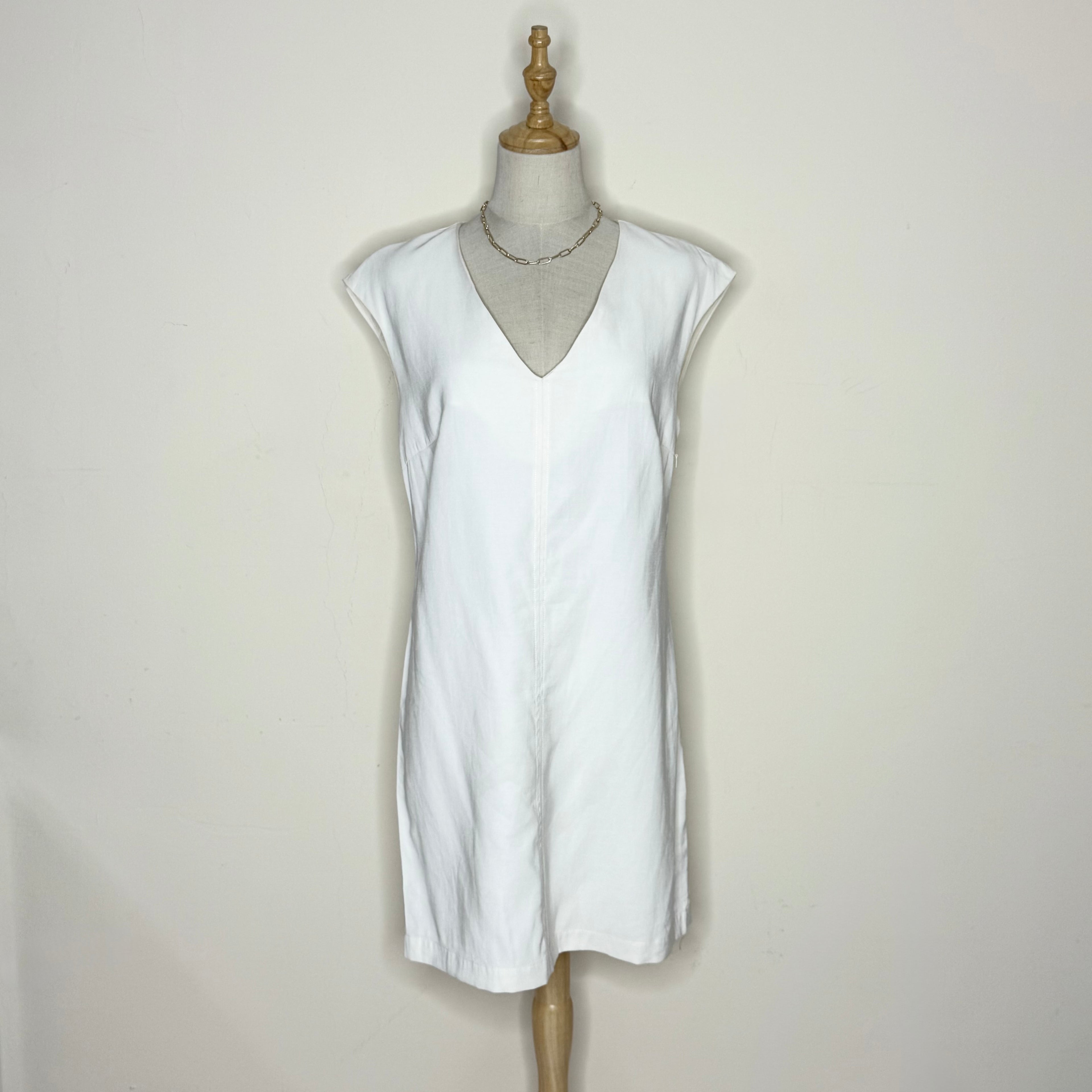 White sleeveless dress on a mannequin against a plain background