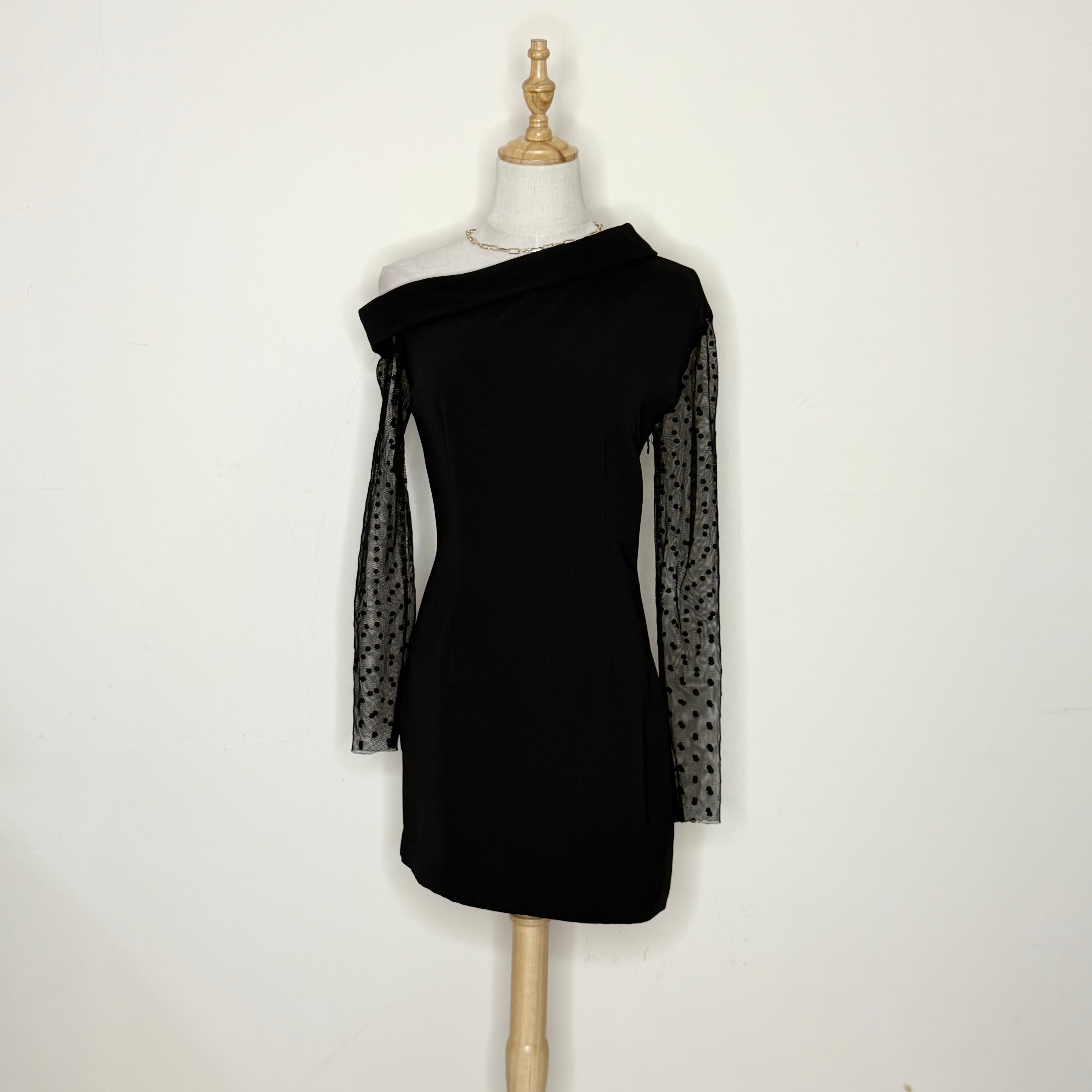 Black dress with sheer sleeves on a mannequin against a white background