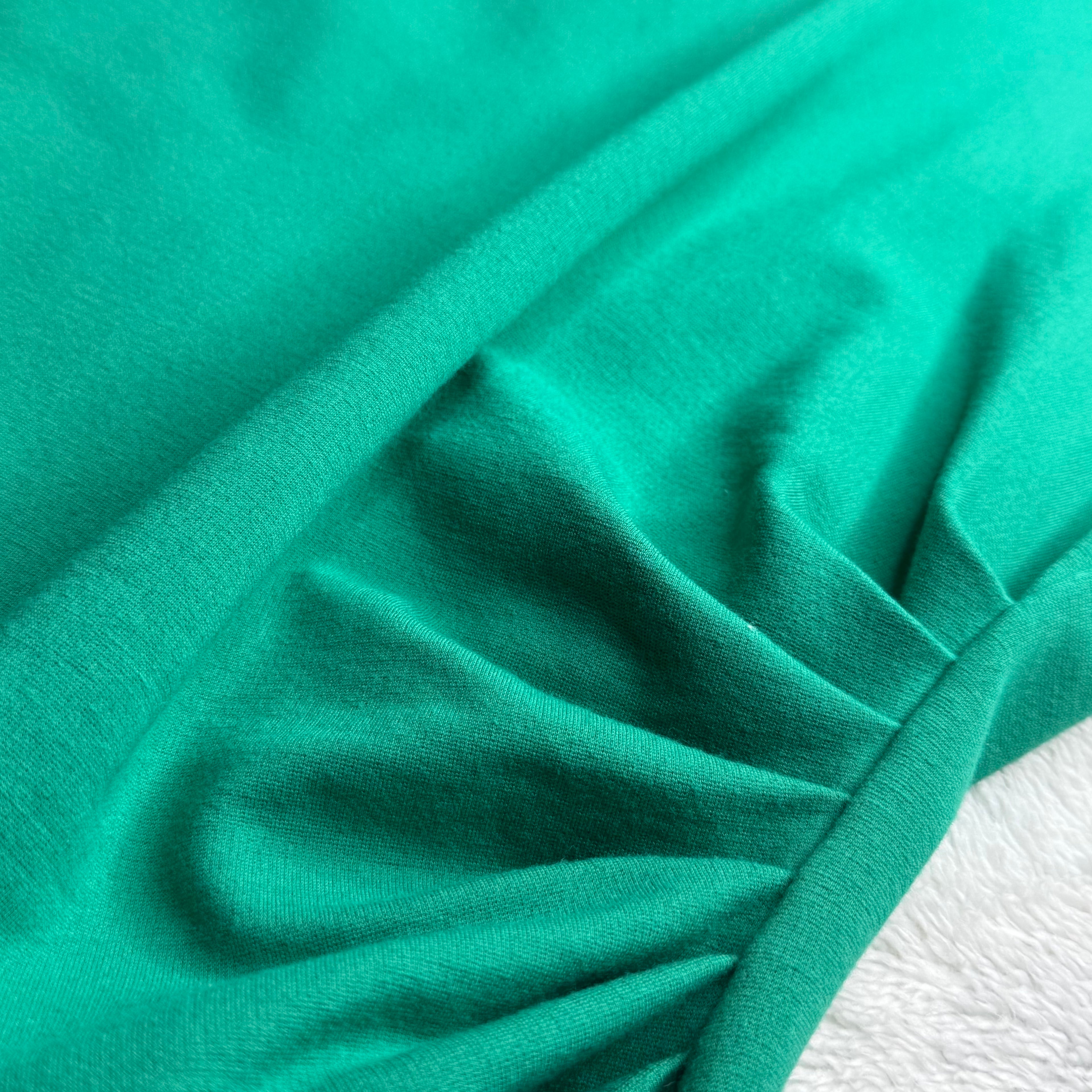 Close-up of teal fabric with folds on a white background