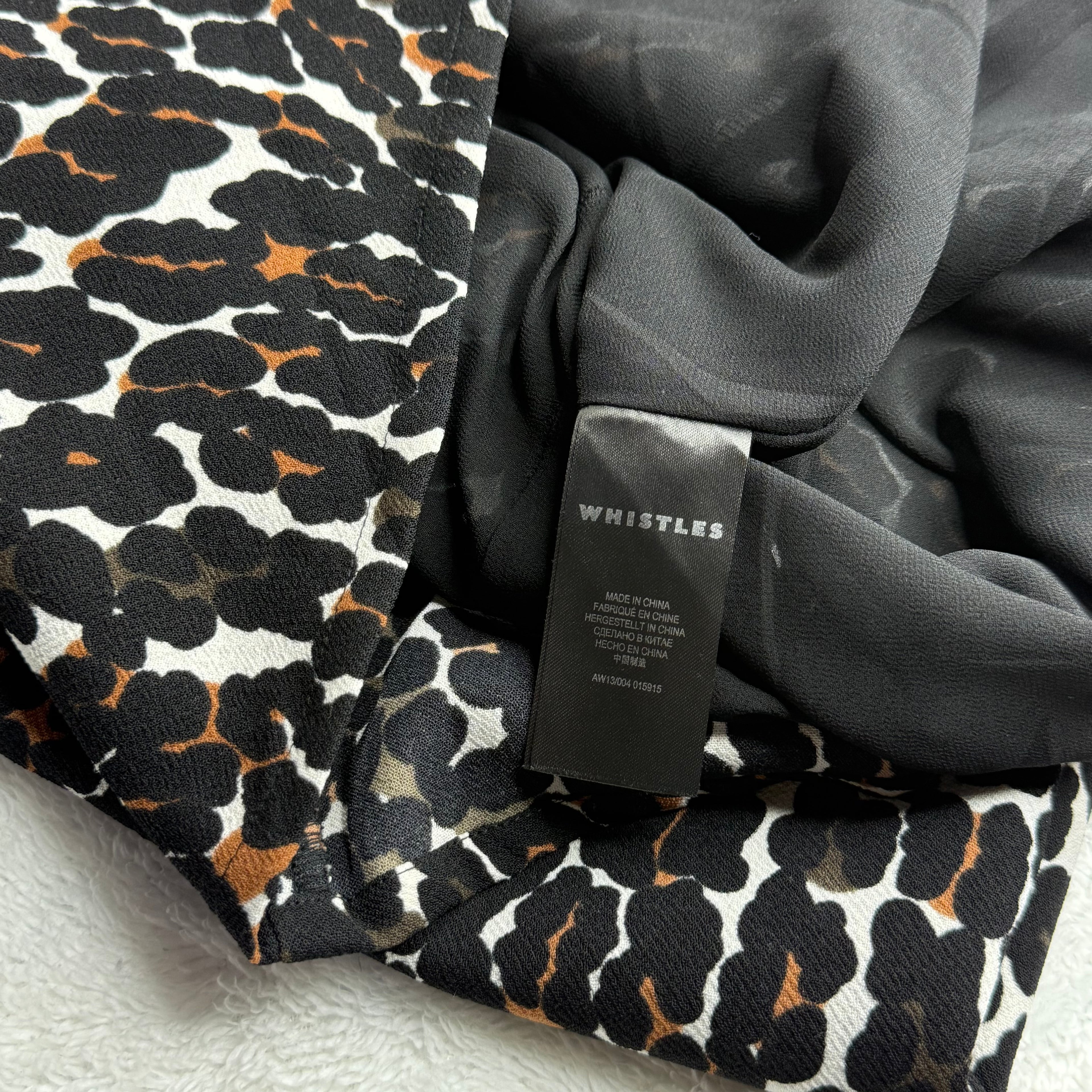 Close-up of a garment with a leopard print pattern and a Whistles tag.