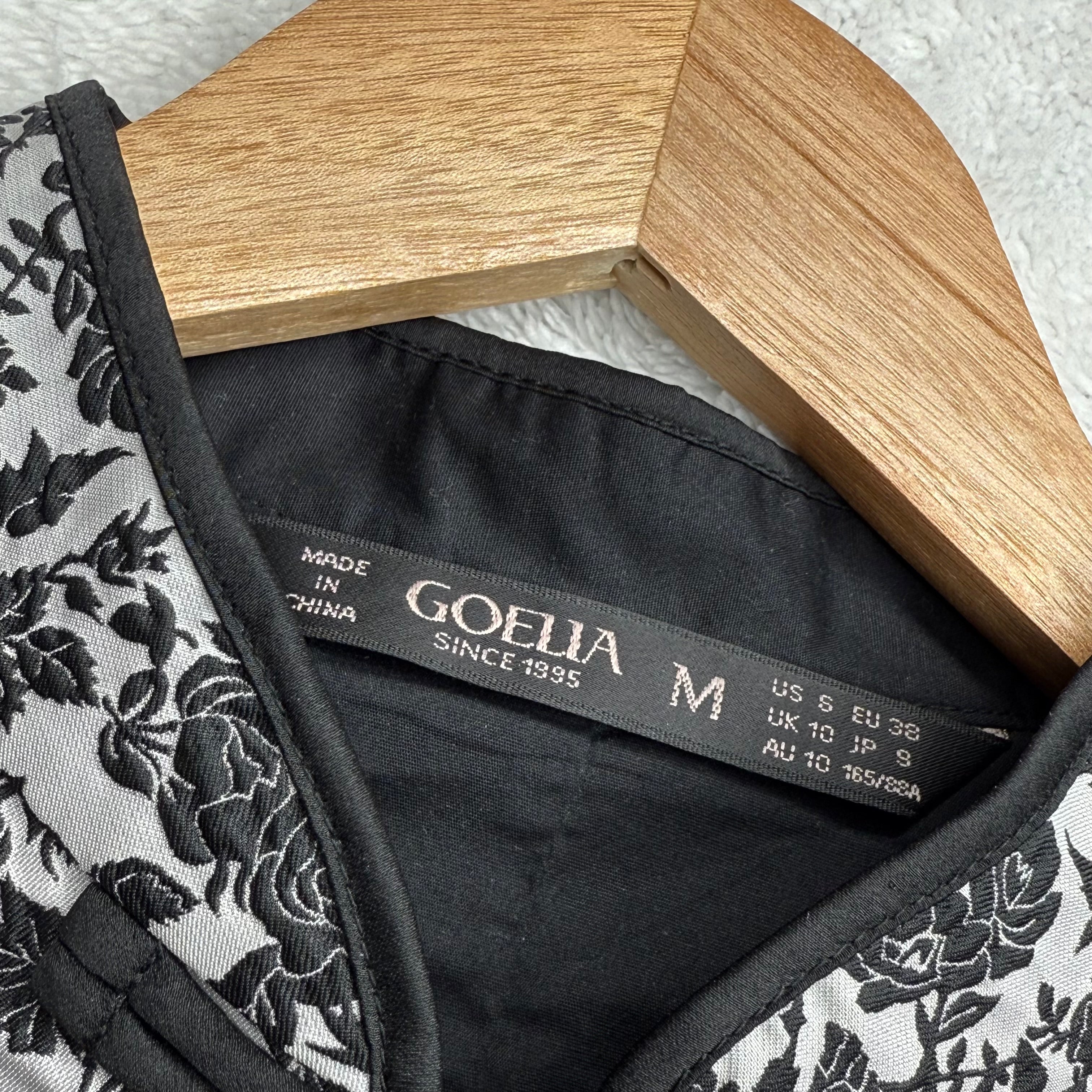 Lace garment with a Goelia label on a wooden hanger